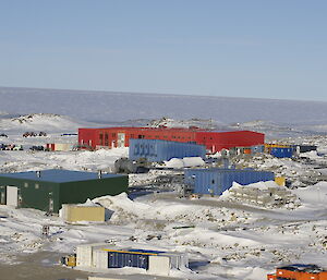 Several large colourful buildings are spread over a snow covered ground.  This is Casey Station.
