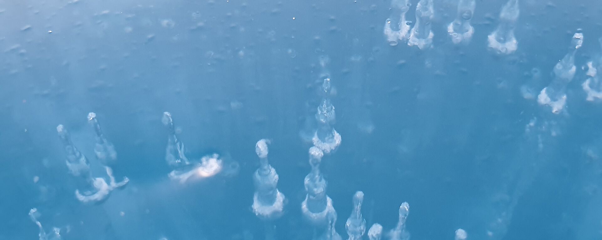 Clear blue lake ice with suspended air bubbles within creating a spectacular effect