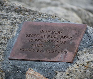 A close up photo of a memorial plaque set into a rock. The plaque reads "In memory, Geoffrey Basil Reeve, 10 February 1939, 6 August 1979, Placed 6 August 1999".