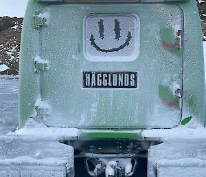 A smiley face has been drawn into the frost on the back window of the green Hägglunds.
