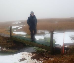 Person standing in the middle of the wooden bridge