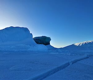 A jade coloured iceberg, surrounded by white icebergs, is frozen into the sea ice.