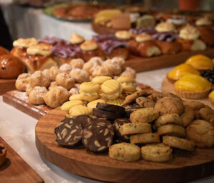 Wooden trays of home-made biscuits, iced buns, and various fruit tarts.