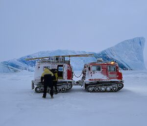 A red vehicle in front of a large blue and white striped iceberg.