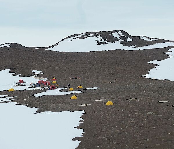 Yellow tents and orange 'melons' on rocky ground.