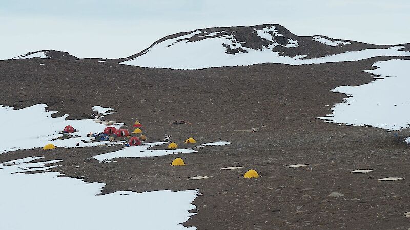 Yellow tents and orange 'melons' on rocky ground.
