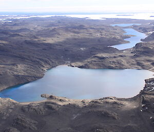 Aerial view of a blue lake surrounded by bare rocky hills
