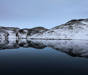 Reflections of snow covered mountains in a dark blue lake