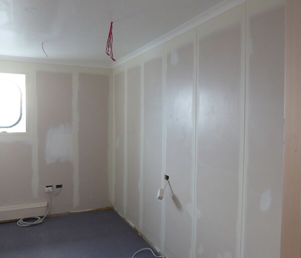 A room is being prepared for painting with walls and ceiling sanded back and seams sealed.