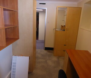 A fully renovated bedroom mwith a wardrobe against the wall next to the door and a desk and bookcase visible in the foreground.