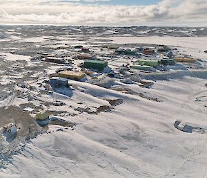 Aerial shot of Davis Station showing numerous coloured buildings set into a snowy and rocky landscape.