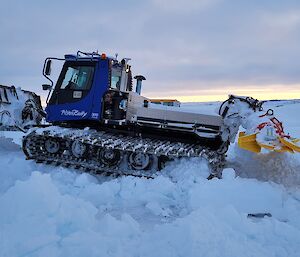 A large tracked vehicle is sitting on the snow after being dug out by expeditioners.