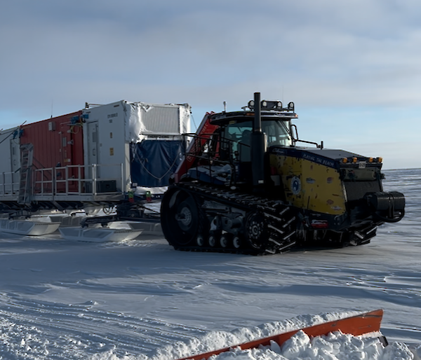 A tractor hauls a paid of sleds ti the camp location.