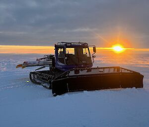 A sunset behind a snow groomer