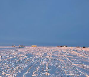 A distant shot of the traverse camp with the golden hour low sun showing definition in the snow.