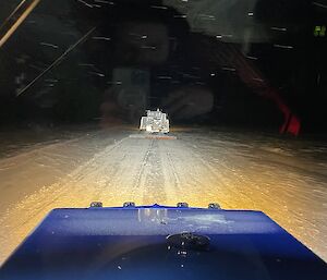Looking out the window of a traverse tractor, showing following another traverse vehicle with sleds in tow.