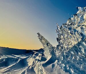 A piece of sea-ice looking like glass with lots of conchoidal fractures, juts vertically out of the sea-ice