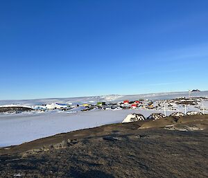 Four graves are visible on a rocky hill overlooking an ice covered harbour. In the distance are a large number of brightly coloured buildings.