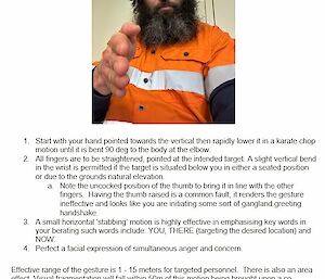 A bearded man wearing an orange tradie shirt faces the camera with his right hand pointed at the camera.