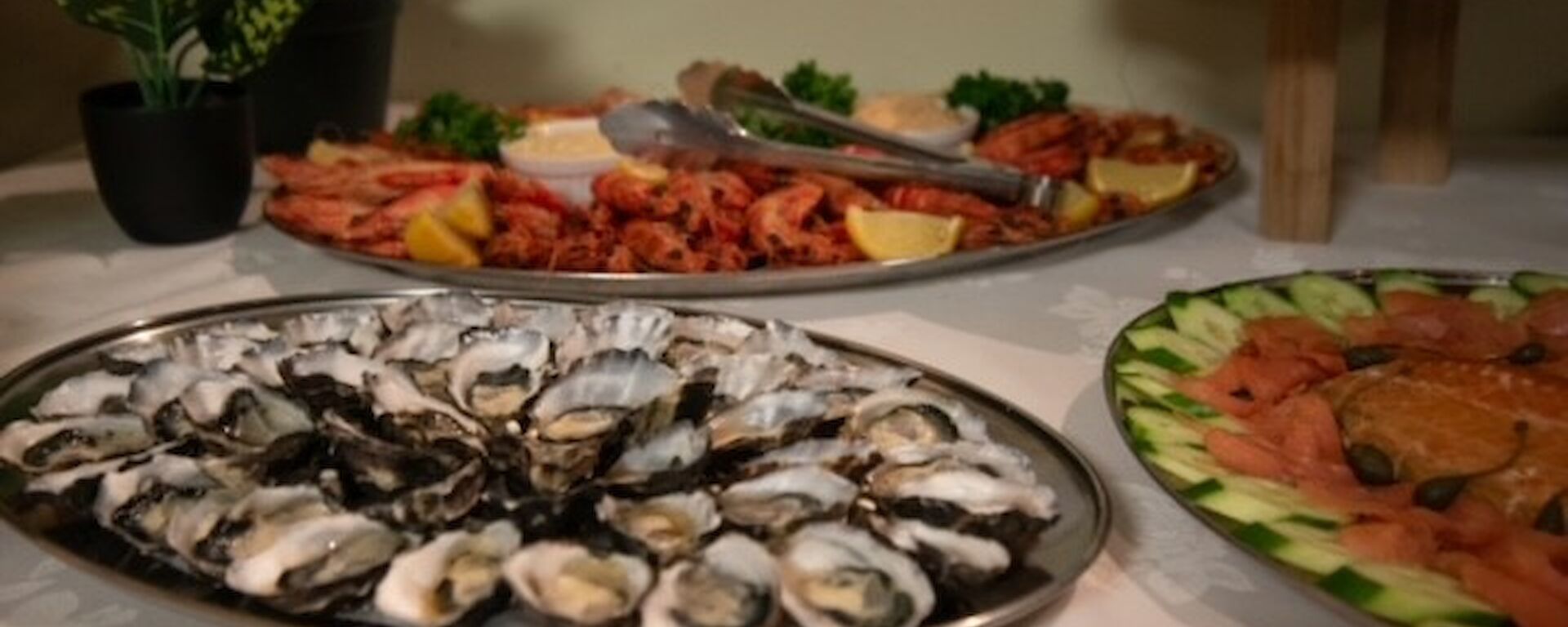 silver trays of oysters, smoked salmon and prawns on a white tablecloth