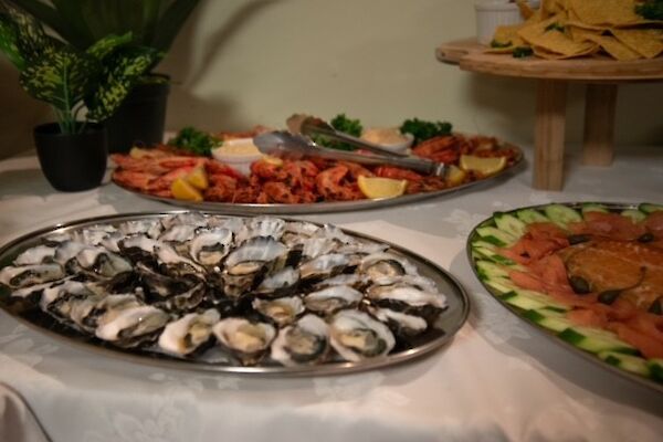 silver trays of oysters, smoked salmon and prawns on a white tablecloth