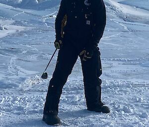 A man is standing on an ice covered landscape holding a golf club.