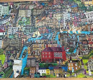 A large jigsaw puzzle of a town with canals is complete on a table.