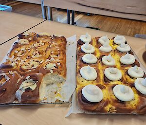 Two trays of freshly baked sweet buns with a bun missing from the corner of one tray