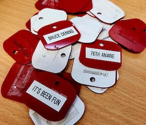 A pile of rectangular red and white plastic tags is sitting on a desk.