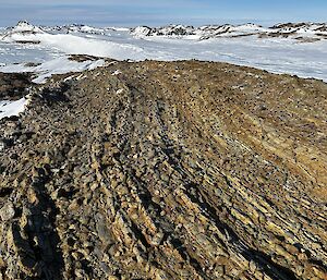 Wear lines from ice and wind action can be seen in this photograph of a rocky, ice covered, landscape.