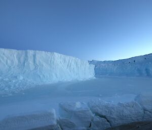 Two icebergs locked in sea ice show signs of crumbling and pitting