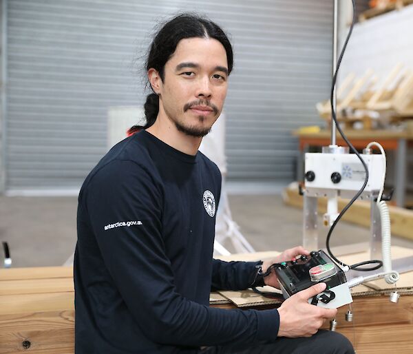 A man holding a small operating console for a scientific instrument.