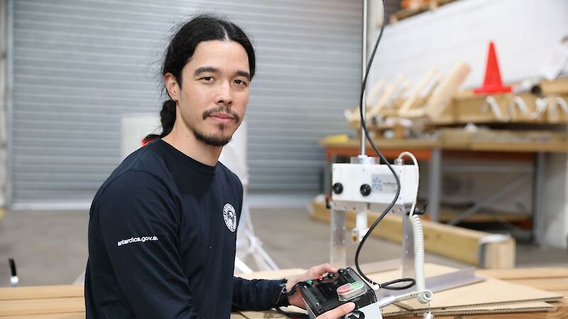 A man holding a small operating console for a scientific instrument.