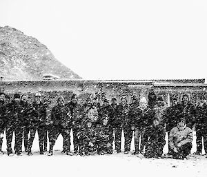 Black and white photo of a group standing in a line with snow falling