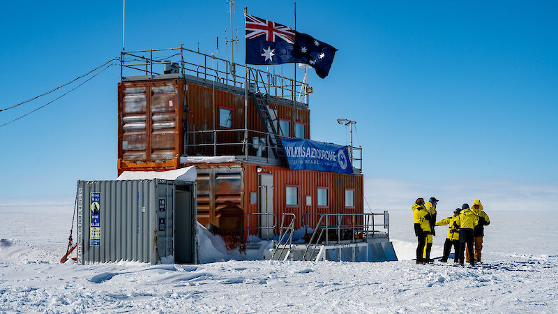 A red shed on the ice with Australian flag and workers in yellow