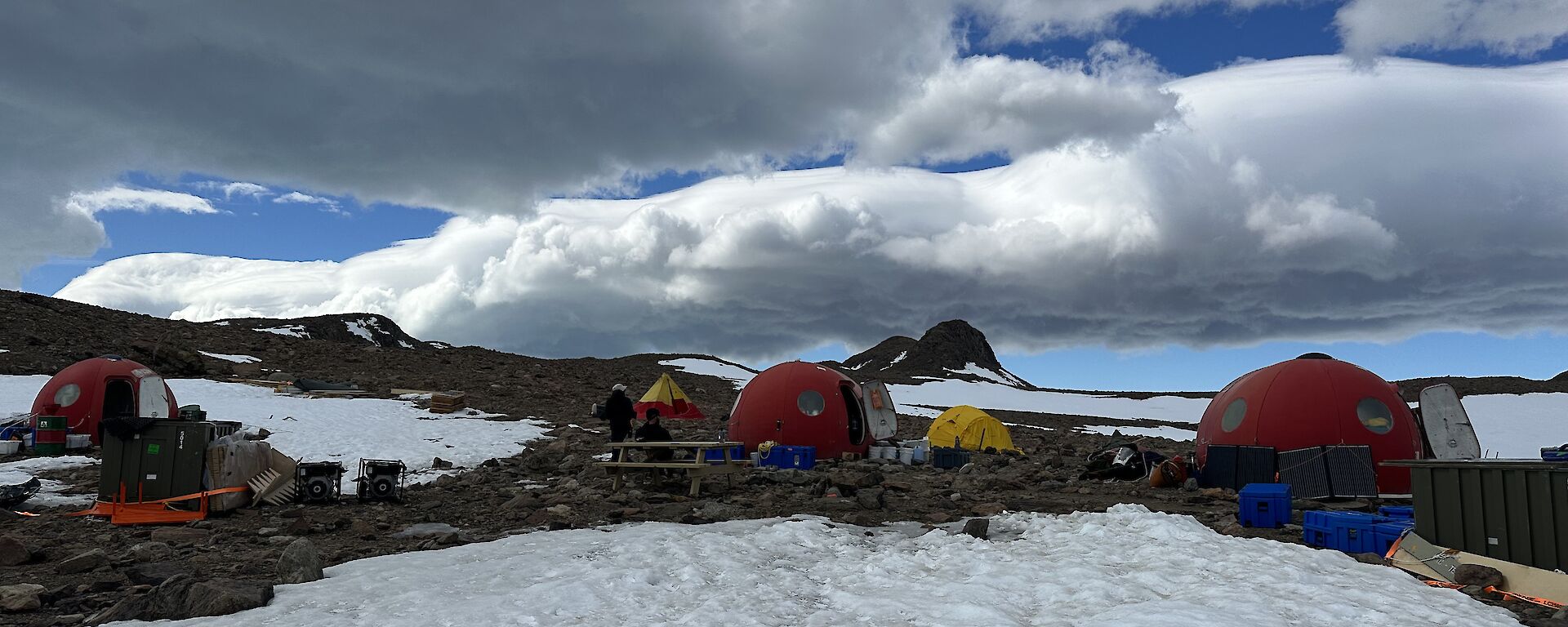 four round red tents stand on ice, with a few yellow normal tents between them