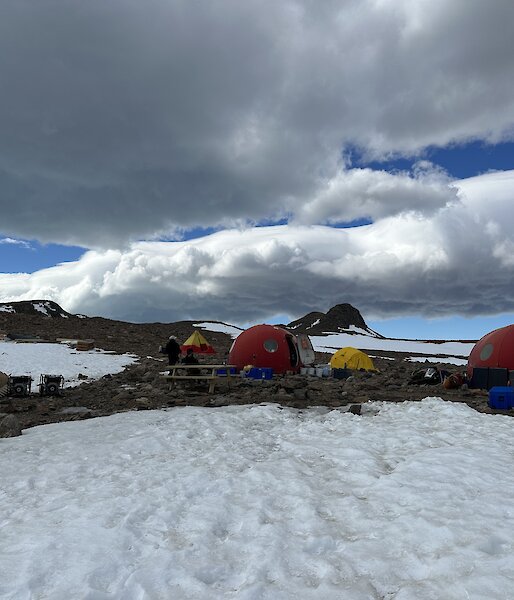 four round red tents stand on ice, with a few yellow normal tents between them