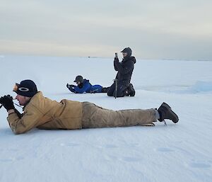 Three expeditioners take photos of seals (not shown).