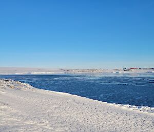 An expeditioner stands overlooking a bay covered in grease ice.