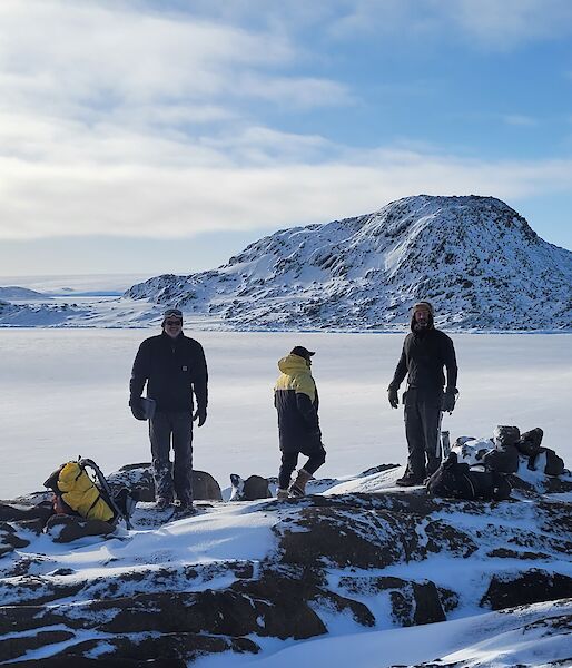 A group stands on a mountain surrounded by mist and icy mountains.