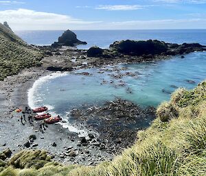 Small cove with grey rock beach and boats pulled up