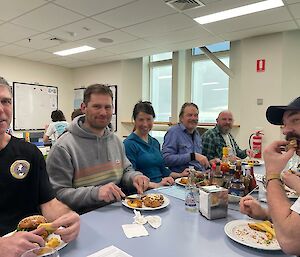 A group of happy Antarctic expeditioners sharing a meal together