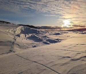 An evening Antarctic vista looking over the snow, ice and coastline to the icebergs on the horizon