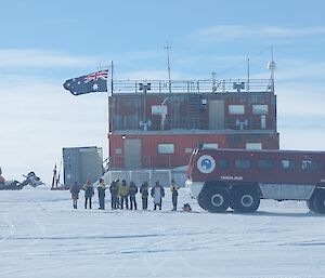 A welcoming party stand with the Terrabus outside the buildings at Wilkins aerodrome