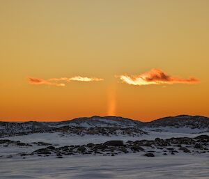 The sun setting behind the snow and ice covered hills