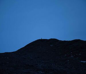 Deep dark blue sky over a black hill.