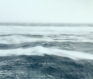 A grease like sea ice can be seen floating on the surface of the sea under an overcast sky