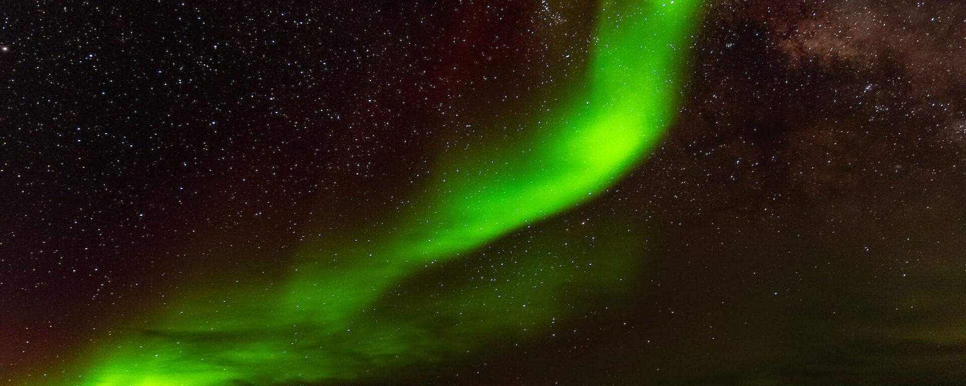Bright green ribbon of light in a star filled night sky.