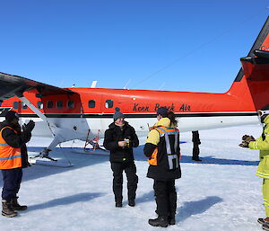 A man is receiving a presentation from a woman in front of a twin engined light aircraft. There are three men watching and clapping.