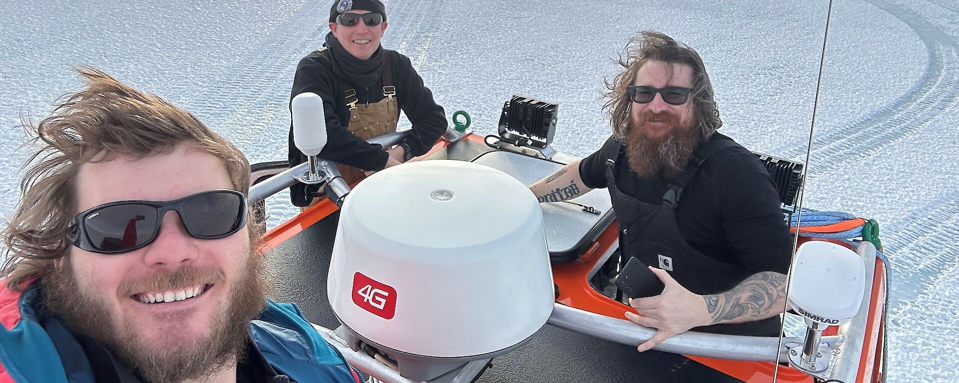 Three dudes in a quad bike on the ice looking very happy
